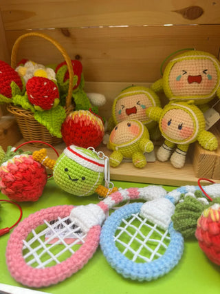 Handmade crochet tennis racquets, strawberries, and cute amigurumi plush toys on display