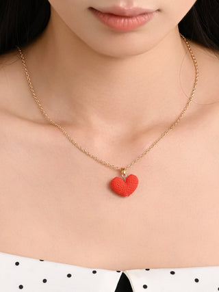 Gold chain necklace with handmade red crochet heart pendant on woman’s neck