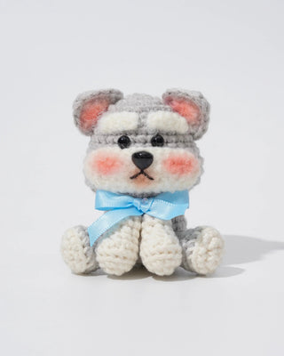 Handmade crochet husky dog amigurumi with blue ribbon and blushed cheeks on white background