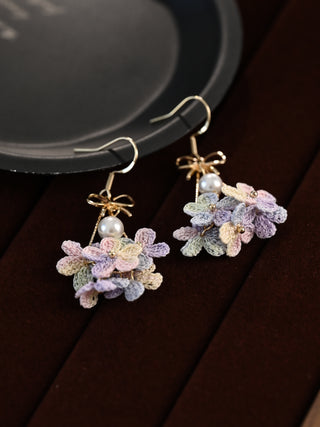 Pair of floral earrings with pastel colors on a dark surface