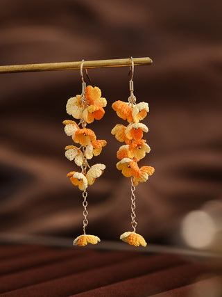Floral earrings with orange and yellow flowers on a brown background