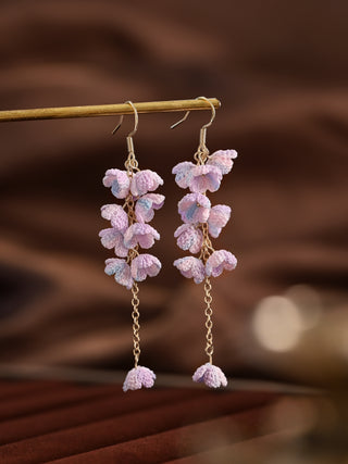 Pink butterfly earrings on a wooden stick with a blurred brown background