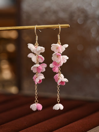Floral earrings with pink and white flowers on a wooden surface