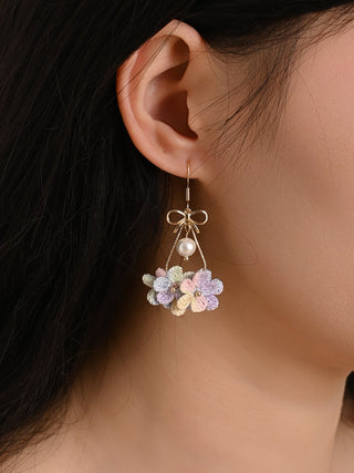 Close-up of a person wearing floral earrings with a neutral background