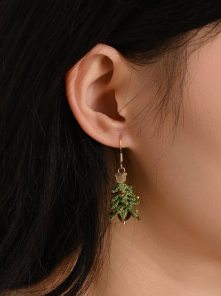 Close-up of an ear wearing a green leaf-shaped earring with a dark background