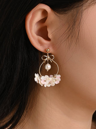 Close-up of a person wearing floral earrings with a neutral background