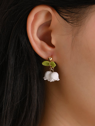 Close-up of an ear wearing a floral earring with a blurred background