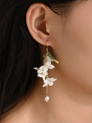 Close-up of an ear wearing a floral earring with a blurred background