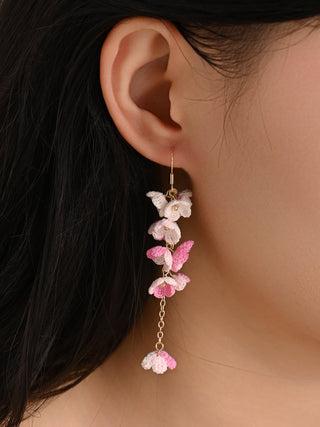 Close-up of a person wearing pink floral earrings with a neutral background