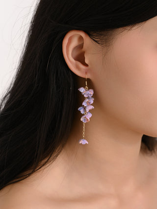 Close-up of a person wearing a floral earring with purple flowers.