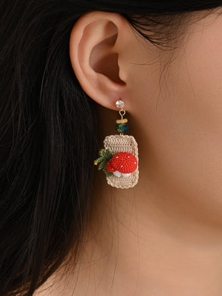 Close-up of an ear wearing a decorative earring with a red gemstone.