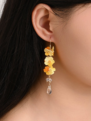 Close-up of a person wearing floral earrings with a neutral background