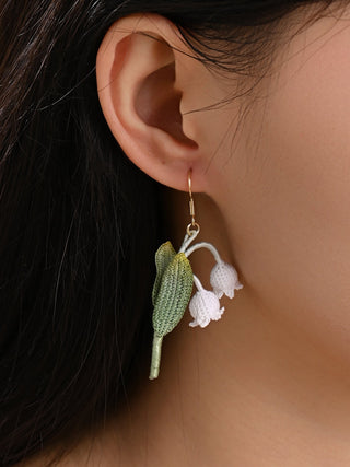 Close-up of a person wearing a floral earring with a neutral background