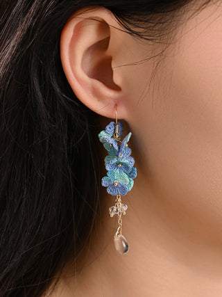 Close-up of a person wearing a floral earring with blue flowers.