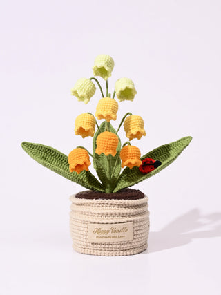 Crochet yellow and orange bell flowers in a handmade pot with green leaves and a crochet ladybug.