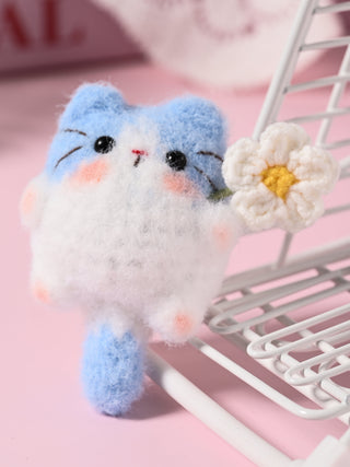 Small plush cat toy with a flower on a pink background