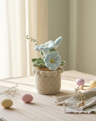Handmade crochet blue flowers in a pot on a wooden table with pastel decorations