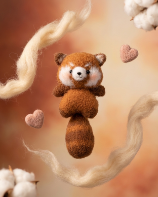 Handmade crochet red panda plush toy with heart accents and cotton decor on soft background