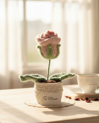 Handmade crochet pink flower in pot with 'To Mum' card, cozy sunlight background